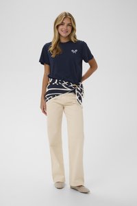 Jūras kara flotes kokvilnas t-krekls ar krustveida raketi; krēmkrāsas plašas bikses; rakstains josta, kas sasieta ap vidukli; neitrālas krāsas plakanas kurpes.