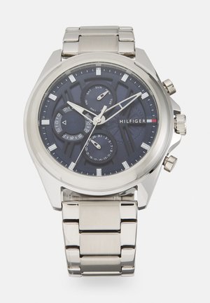 Stainless steel watch with a dark blue dial, three sub-dials, silver hands, and a date function. Features a link bracelet and crown on the side.