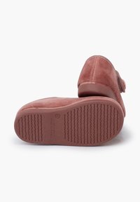 Zapatillas de ante rosa con puntera redonda, suela texturizada y detalle de lazo decorativo. Material suave con un acabado liso en la parte superior.
