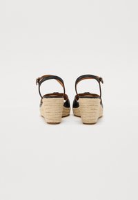 Svarta läder kilklacksandaler med ankelsnoddar, med strukturerade juteinlindade klackar och en slät innervadding.
