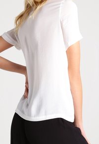 Vit kortärmad t-shirt i slät tyg, med en enkel design, rundad halsringning och rak nederkant.