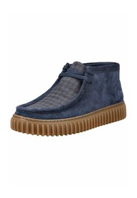 Dark blue suede chukka boots with a textured gray fabric panel, flexible gum sole, and decorative lacing across the front.