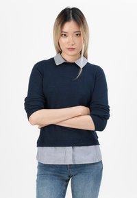 Marineblauer Strickpullover mit einem gestreiften Hemd darunter, langen Ärmeln, gerippten Bündchen und geradem Saum.