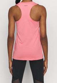 Débardeur de sport sans manches rose fabriqué en tissu léger avec une texture lisse. Présente un design dos nageur et une étiquette "AEROREADY" au dos.