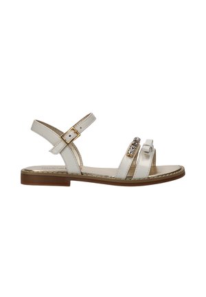 Witte platte sandaal met enkelriem en gesp, en twee voorste bandjes, waarvan één versierd met strasssteentjes en een strikdetail, bruine zool.