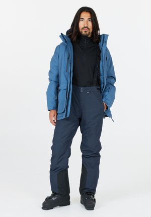 Blue waterproof jacket over a black base layer, paired with dark blue pants featuring black accents and boots, designed for outdoor activities.