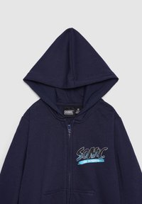 Felpa con cappuccio con zip blu navy con un grande logo "SONIC" in bianco e blu sul petto, con cappuccio foderato e tessuto morbido.