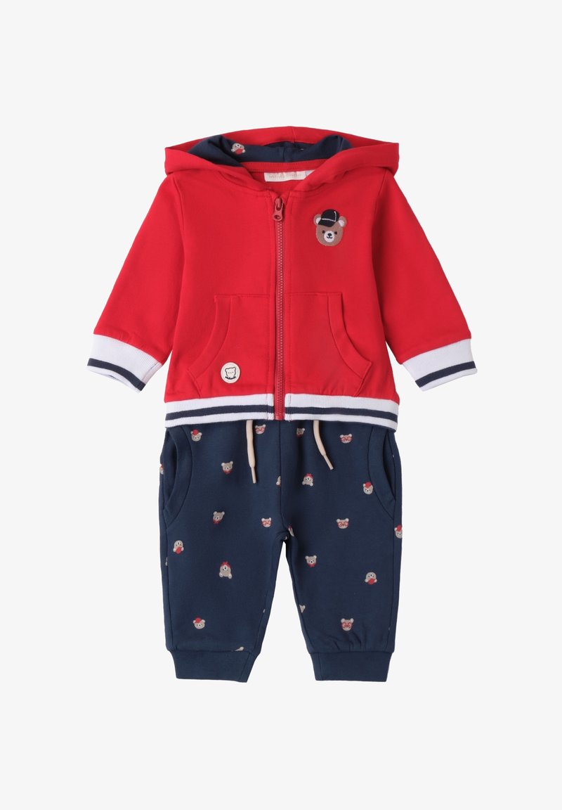 Czerwony dwuczęściowy strój składający się z bluzki z kapturem z zamkiem błyskawicznym z aplikacją misia oraz granatowych spodni z małym wzorem misiów i sznurkiem w talii.