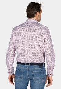 Lange mouwen overhemd in lichtroze met een patroonontwerp met kleine rode en blauwe motieven. Knopmanchetten en een klassieke kraag. Draag met jeans.