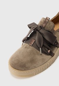 Scarpa in suede grigia con punta arrotondata, dotata di lacci in tessuto larghi e aglet in metallo. Suola con texture e dettagli di cucitura lungo il bordo.