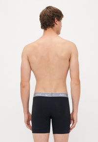 Črne raztegljive bokserice z teksturiranim sivim Nike pasom, ki imajo srednje visok kroj in tesen fit.