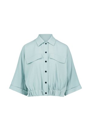 Chemise courte bleu clair à manches courtes, boutons noirs sur le devant, deux poches poitrine avec rabats, et taille élastique.