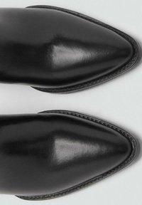 Czarne skórzane buty na szpilce z wysmuklonym noskiem, o gładkiej fakturze i widocznym przeszyciu wokół krawędzi, prezentujące minimalistyczny design.