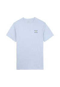 T-shirt en coton bleu clair à manches courtes et col rond, arborant un petit motif floral vert et jaune sur le côté gauche de la poitrine.