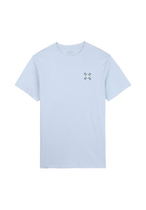 T-shirt en coton bleu clair à manches courtes et col rond, arborant un petit motif floral vert et jaune sur le côté gauche de la poitrine.