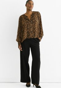 Leopard print blouse in brown and black with a V-neck, long sleeves, and buttons. Paired with wide-leg black trousers and heels.