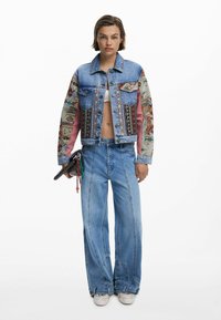 Denim jacket met kleurrijke, geguikte mouwen, fitted ontwerp en decoratieve knopen. Gecombineerd met wijde jeans en een clutch.