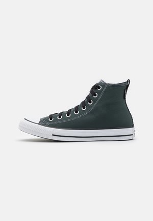 Czarne sneakersy z wysoką cholewką z płótna z białą gumową podeszwą, czarnymi sznurowadłami i srebrnymi oczkami, pokazane z boku na neutralnym tle.