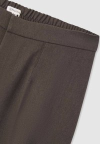 Pantaloni marroni scuri con una vita elastica, tessuto a trama liscia e cuciture laterali. Presenta un'etichetta con la dicitura "TERRANOVA" sulla vita.