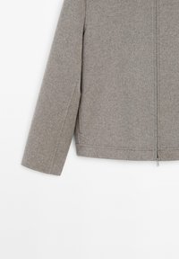Grå zip-up jacka i strukturerad tyg, med långa ärmar, rak passform och en minimalistisk design. Subtila sömnadsdetaljer.