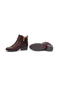 Stivali ankle in pelle marrone con zip laterale, tacco impilato e dettaglio decorativo con fibbia. Texture liscia e design sagomato.