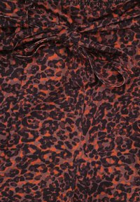 Leopardprint stof in donkerbruin en oranje, met een tailleband voorzien van een decoratieve strik en een zachte textuur.