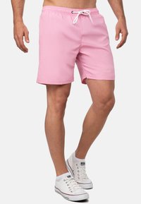 Costumi da bagno rosa con cintura elastica e lacci bianchi. Realizzati in materiale leggero, presentano tasche laterali e un design slim fit.