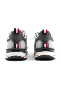 Šedé sportovní boty s texturovaným svrškem, zdobené červenými, bílými a modrými akcenty, s tvarovaným podpatkem a tečkovanou podrážkou.