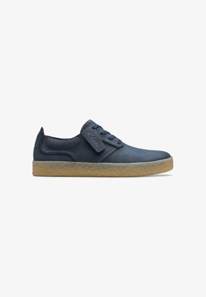 Navy blue low-top leather shoe with suede finish, blue laces, Clarks logo tab, and light brown crepe rubber sole.