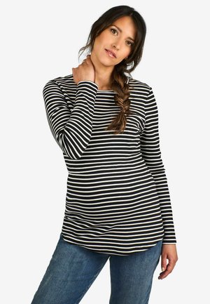 Langærmet top i sort og hvid stribe, med rund halsudskæring og slim fit. Parret med blå jeans lavet af glat, struktureret stof.