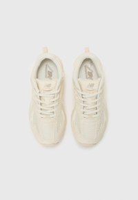 Lys beige løpet skor med mesh og syntetisk overdel, flate lisser, polstrede såler, og New Balance-logo på tungen og siden.