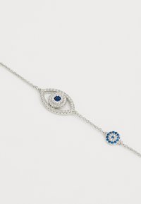 Pulsera de plata con un colgante en forma de ojo que tiene una piedra central azul rodeada de pequeñas piedras claras, y un charm circular con acentos azules.