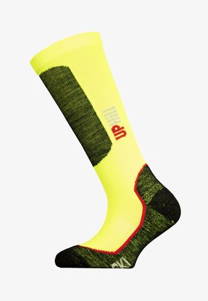 Knielange Socke in leuchtendem Gelb mit grünen Akzenten, strukturiertem Stoff, rotem Bündchen am Knöchel und "UP" in Grau an der Seite bedruckt.