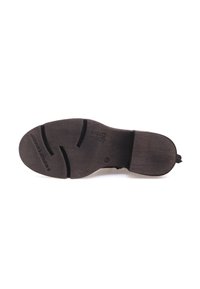Suola di scarpa in pelle nera con superficie testurizzata e scanalature. Presenta una punta arrotondata e un tacco leggero. Marchio impresso sulla superficie della suola.