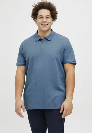 Blauwe textuur polo met een kraag, korte mouwen en een drieknoopsluiting. Geen zichtbare patronen of logo's. Draag het met een donkere broek.