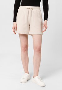 Béžové bavlněné kraťasy s elastickým pasem a šňůrkou na stažení. Mají boční kapsy a uvolněný střih, končící nad koleny.