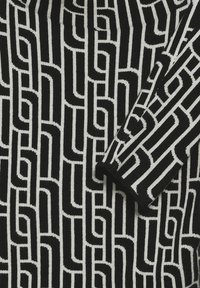 Tessuto a motivi bianco e nero caratterizzato da audaci design geometrici con linee spesse e sottili alternate. Texture morbida, costruzione a maglia.