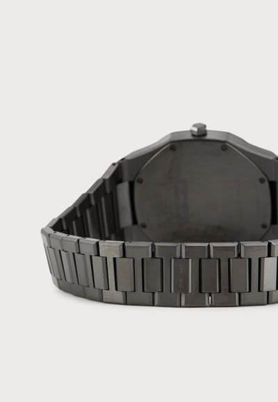 Černé kovové hodinky s osmiúhelníkovým pouzdrem a náramkem na články, s hladkým povrchem a lesklými akcenty, pohled zezadu.