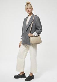 Szary marynarka w prążki na kremowej bluzce, zestawiona z białymi spodniami o szerokich nogawkach i czarnymi butami na platformie. Beżowa torebka na ramię dopełnia całość.
