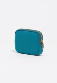 Monedero de color verde azulado con textura suave. Presenta bordes redondeados y un acento de cremallera dorada, diseño compacto y en forma cuadrada.