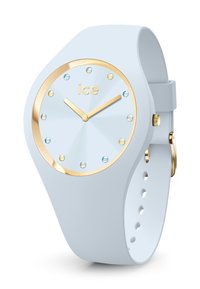 Montre en silicone bleu clair avec un cadran rond, accents dorés, marqueurs en cristal et un cadran lisse et texturé. Aiguilles des heures et des minutes dorées.