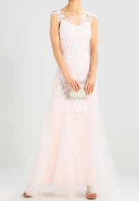 Larga elegancia rosa con apliques de encaje floral, escote transparente y mangas cortas. Falda de tul fluida y un bolso brillante.