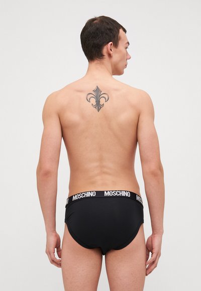 Maillots de bain noirs avec un logo "Moschino" blanc sur la ceinture. Coupe ajustée, texture lisse et sans motifs ni accents visibles.