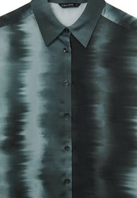 Chemise boutonnée en soie vert foncé avec un motif dégradé, dotée d'un col pointu et de cinq boutons noirs à l'avant.