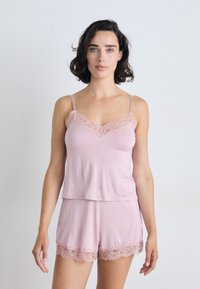 Pink cotton sleep set featuring a camisole with lace trim and matching shorts with lace accents at the hem, both in a relaxed fit.