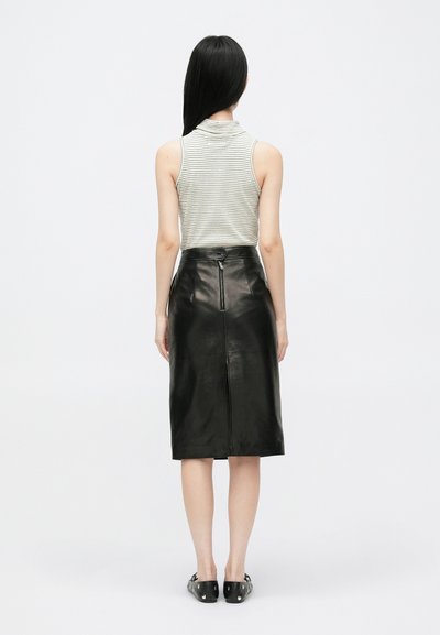 Stribet ærmeløs top med høj krave, parret med en sort læder blyantskørt med en baglomme og en tætsiddende silhuet.