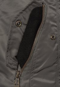 Gray jacket fabric with a black fleece lining visible inside a zippered pocket. Features a metal zipper and snap closure detail.