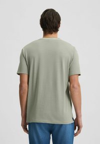 T-shirt verde a maniche corte con colletto rotondo, tessuto morbido e vestibilità ampia. Presenta un design pulito e semplice senza motivi visibili.
