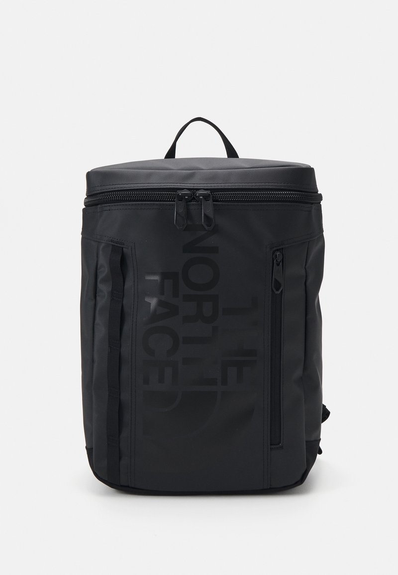 Sac à dos rectangulaire noir avec poche zippée verticale et logo "The North Face" à l'avant, poignée supérieure et fermeture à double zip en haut.