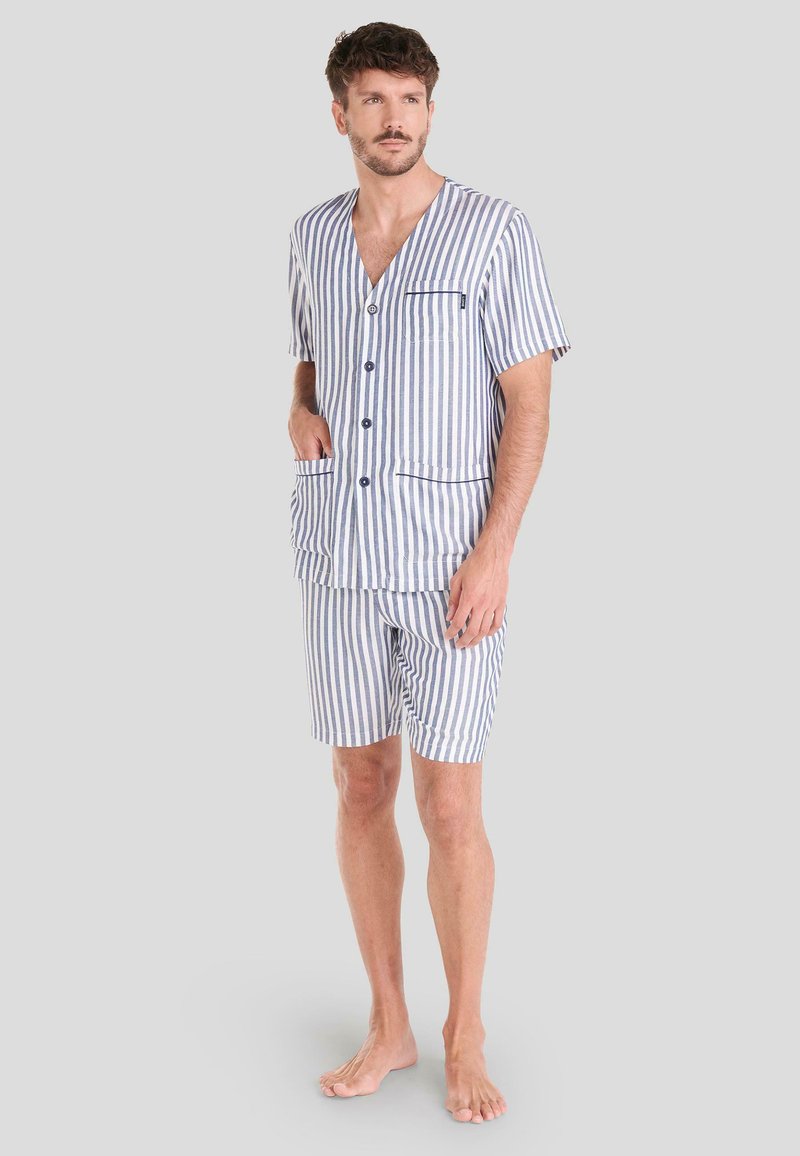 Conjunto de pijama a rayas en azul y blanco, con parte superior de manga corta y escote en V, dos bolsillos frontales, acompañado de pantalones cortos a juego hasta la rodilla.